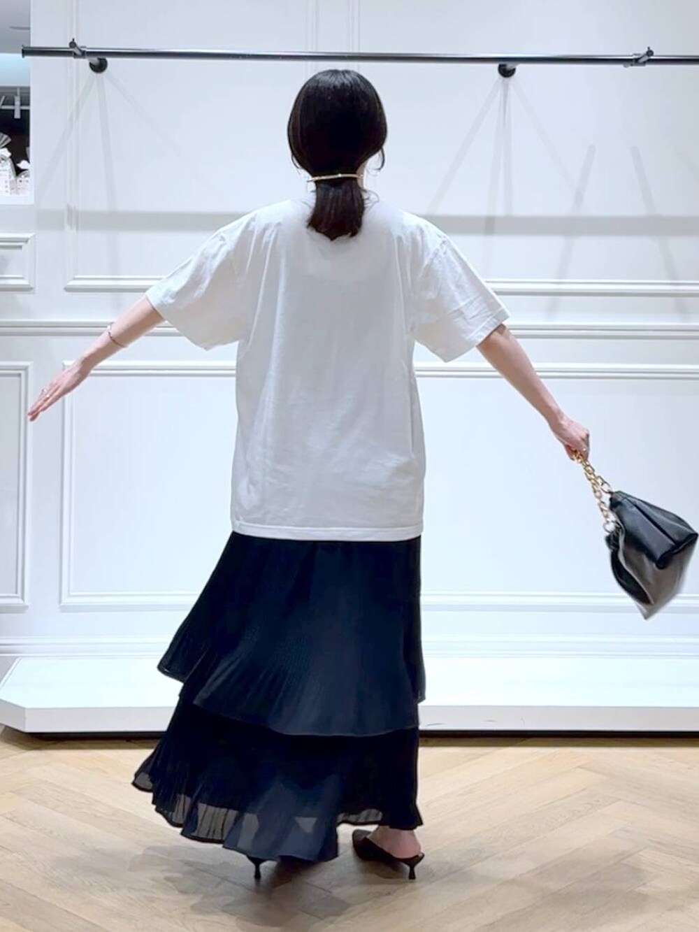 ブラック系のスカート、ホワイト系のTシャツ/カットソー、ブラウン系のパンプスを着用したレディースの秋コーディネートの4枚目の写真