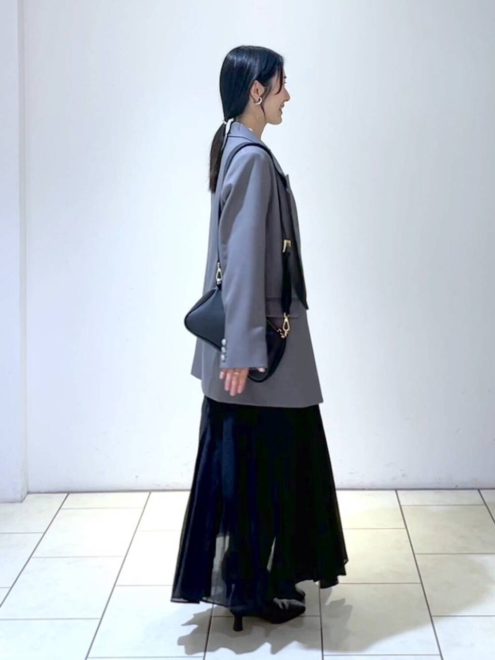 ブルー系のニット/セーター、ブラック系のショルダーバッグ、ブラック系のスカートを着用したレディースの春コーディネートの3枚目の写真