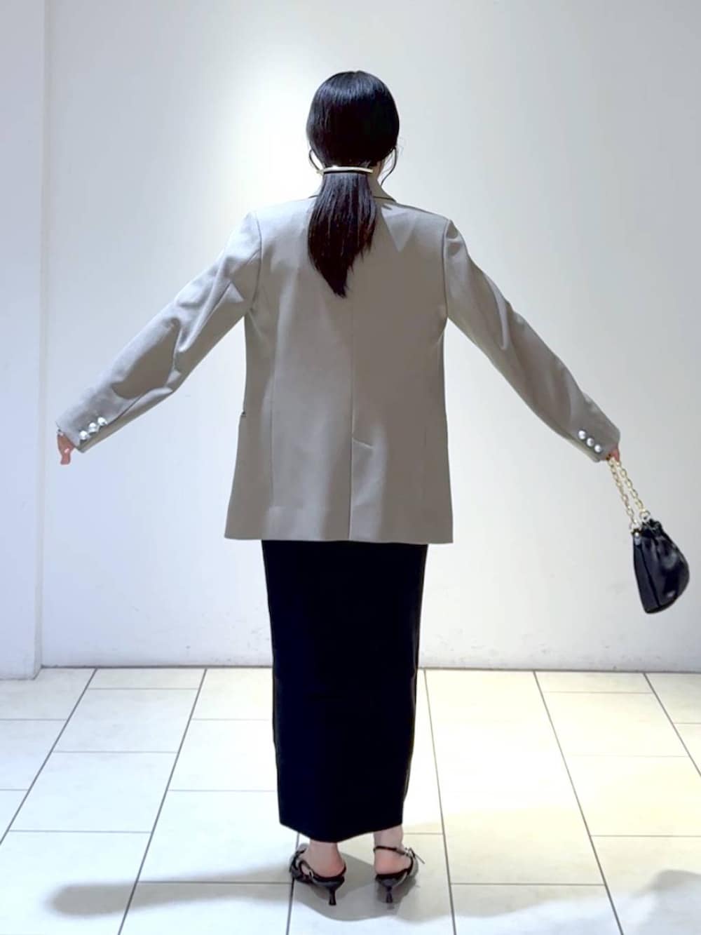 ホワイト系のワンピース、ブラック系のパンプス、グレー系のテーラードジャケットを着用したレディースの冬コーディネートの5枚目の写真