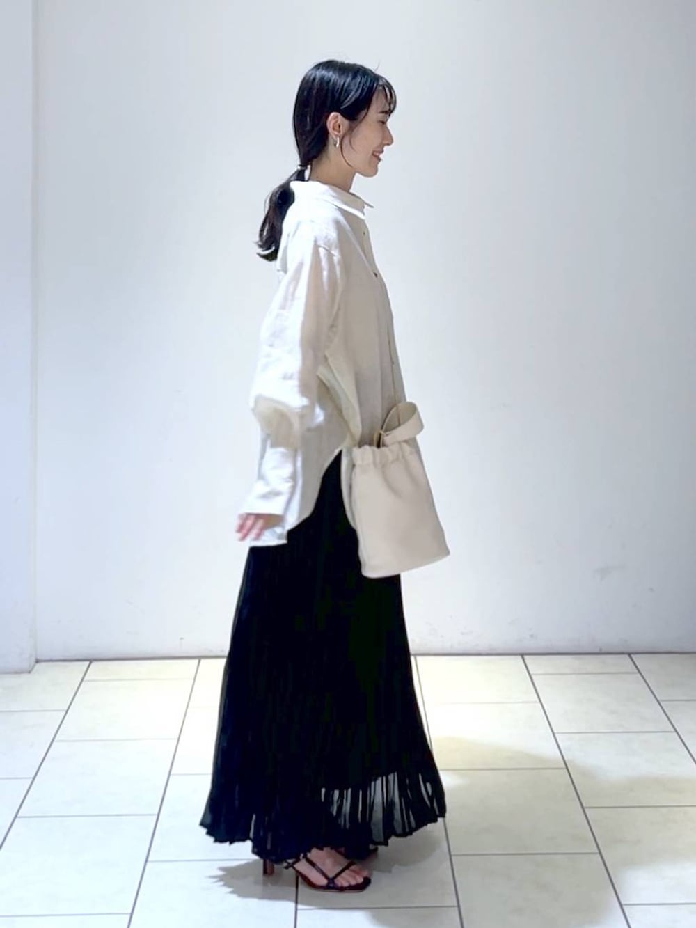 ベージュ系のシャツ/ブラウス、ブラック系のスカート、ホワイト系のショルダーバッグを着用したレディースの夏コーディネートの3枚目の写真