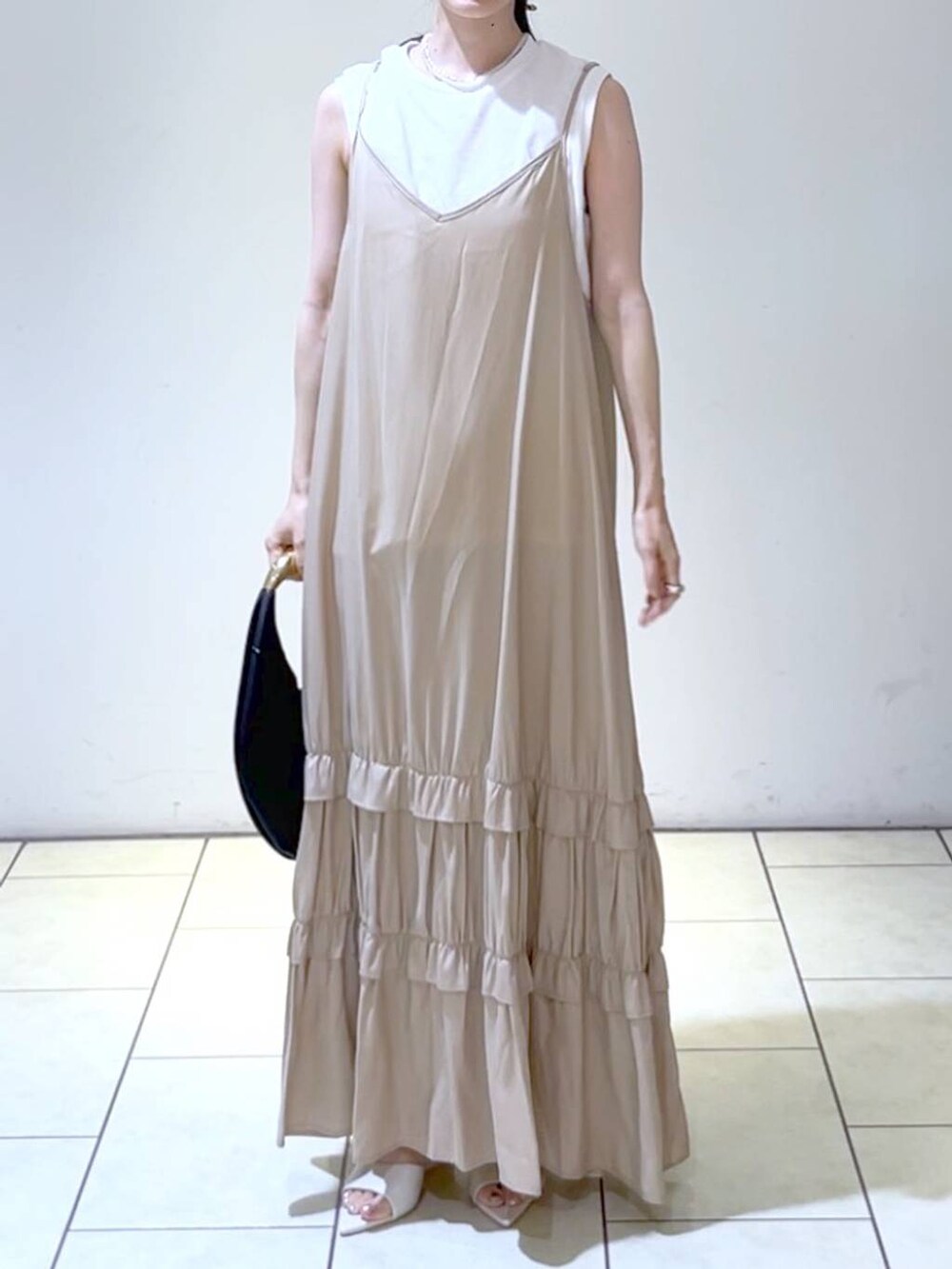 ホワイト系のサンダル、ブラック系のハンドバッグ、ベージュ系のワンピースを着用したレディースの夏コーディネートの2枚目の写真