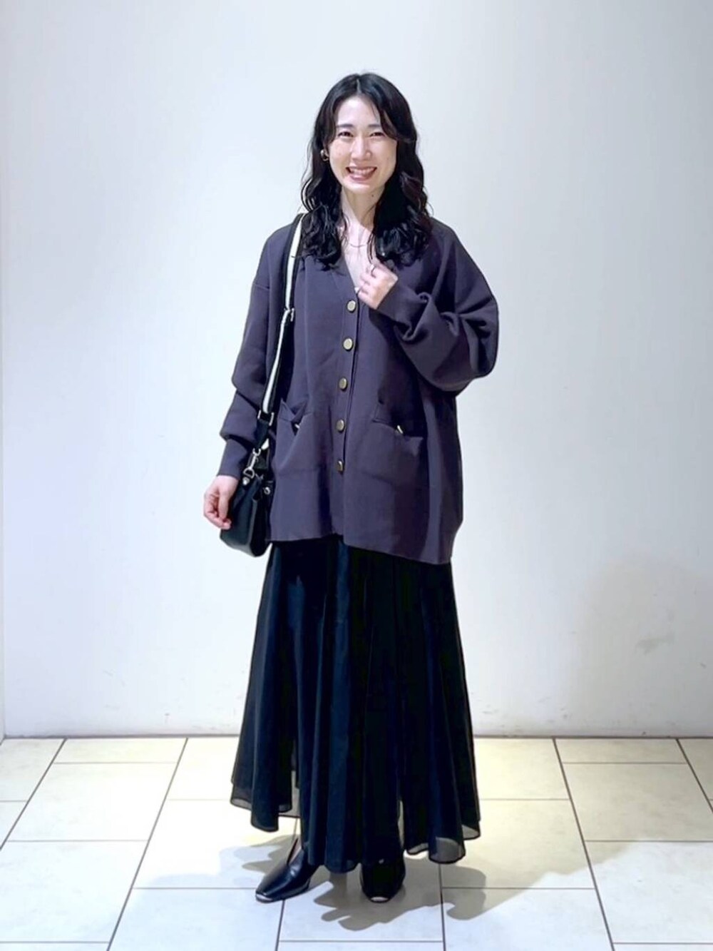 ブラック系のショルダーバッグ、ブラック系のスカート、ブラック系のパンプスを着用したレディースの春コーディネートの6枚目の写真