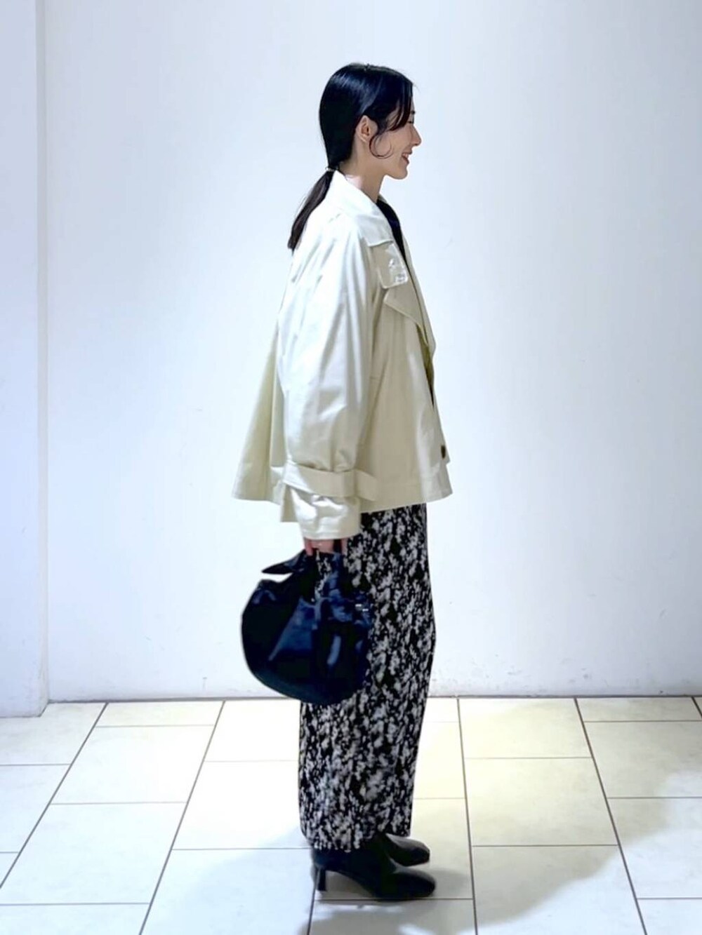 ブルー系のニット/セーター、グレー系のスカート、ブラック系のブーツを着用したレディースの春コーディネートの3枚目の写真