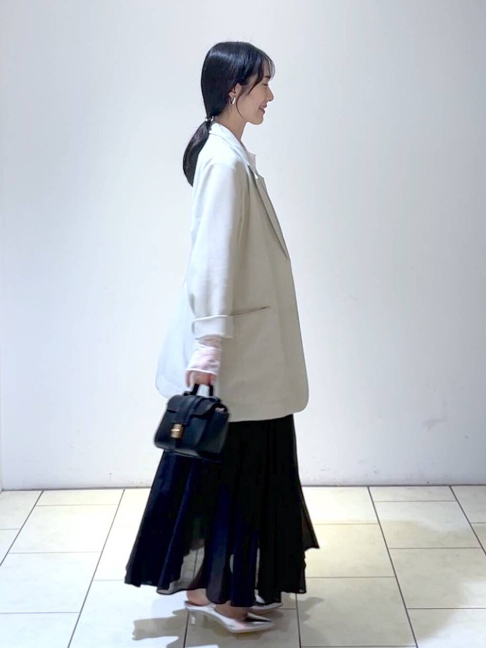 ホワイト系のTシャツ/カットソー、シルバー系のサンダル、ブラック系のスカートを着用したレディースの春コーディネートの3枚目の写真