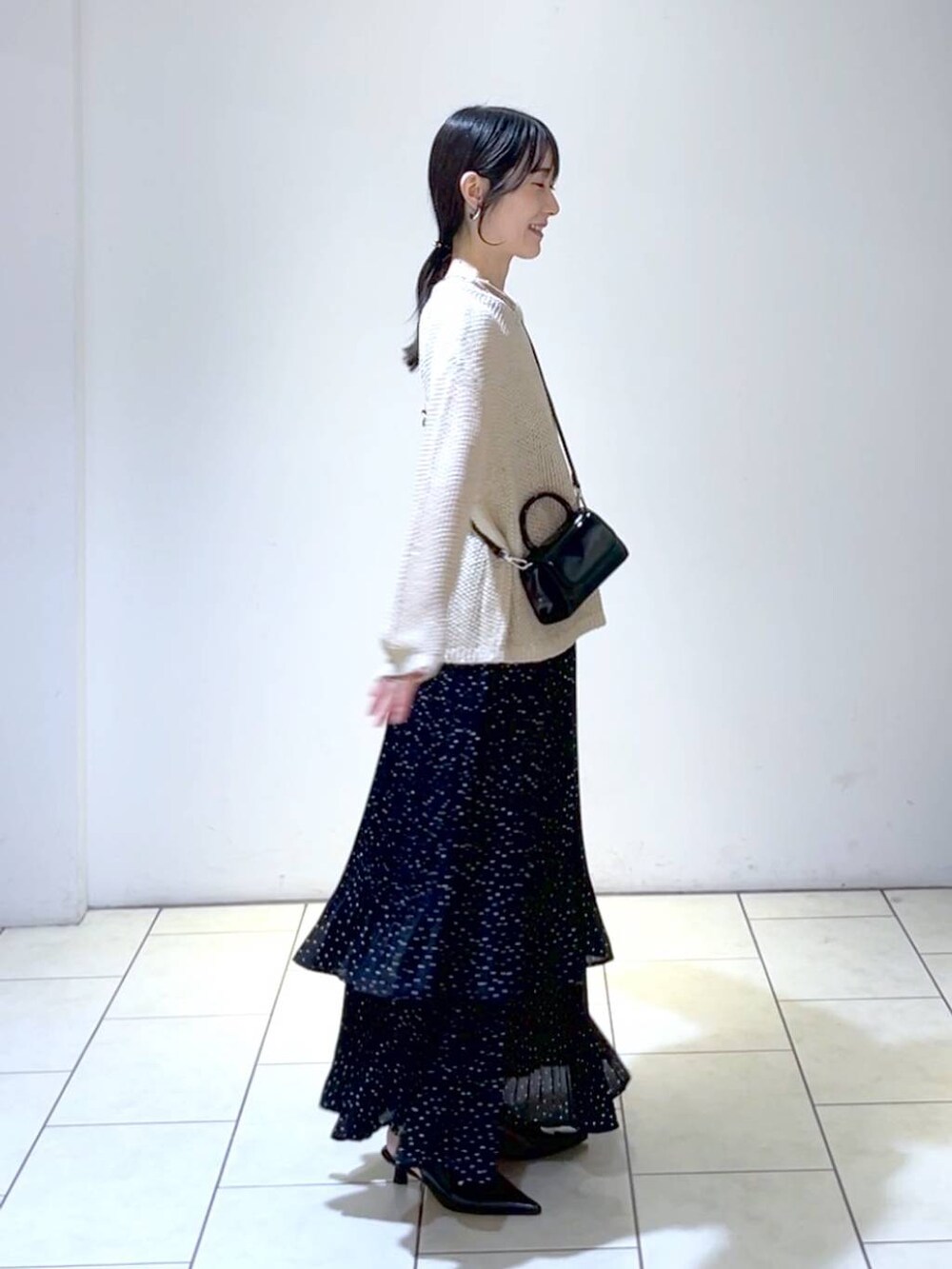 ベージュ系のニット/セーター、ブラック系のパンプス、グレー系のスカートを着用したレディースの秋コーディネートの3枚目の写真