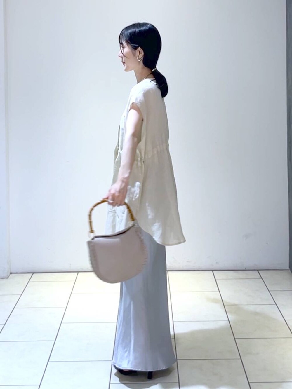 ベージュ系のショルダーバッグ、ベージュ系のベスト、ブルー系のスカートを着用したレディースの夏コーディネートの5枚目の写真