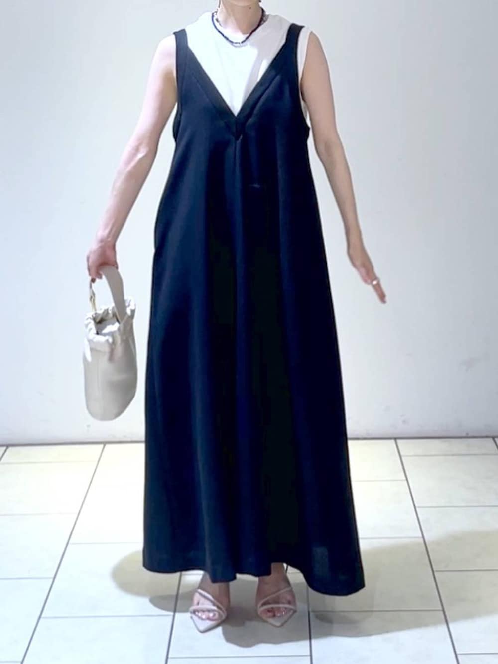 ホワイト系のサンダル、ブラック系のジャンパースカート、ホワイト系のショルダーバッグを着用したレディースの夏コーディネートの2枚目の写真