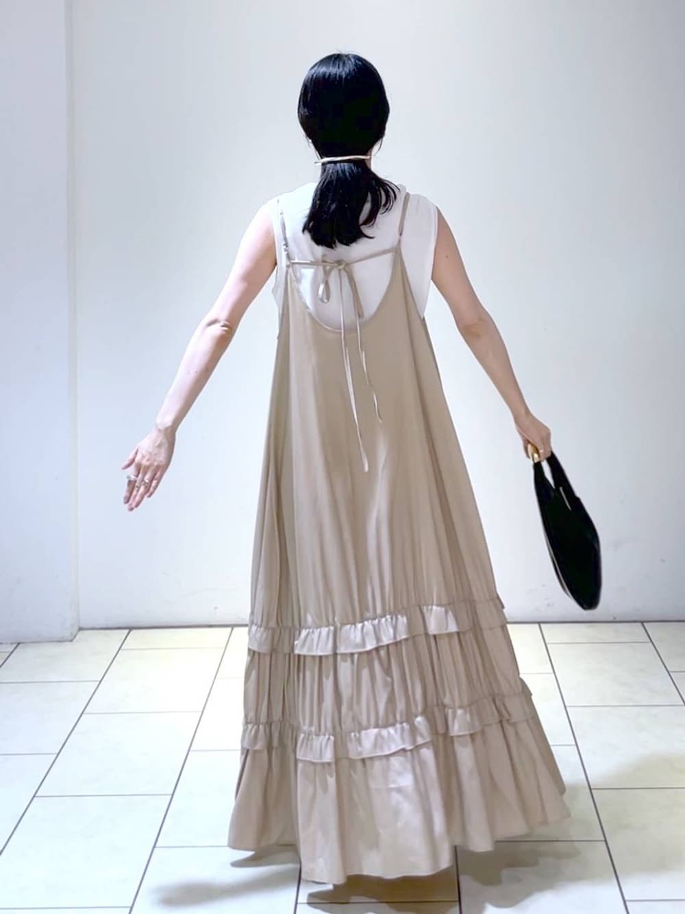 ホワイト系のサンダル、ブラック系のハンドバッグ、ベージュ系のワンピースを着用したレディースの夏コーディネートの4枚目の写真