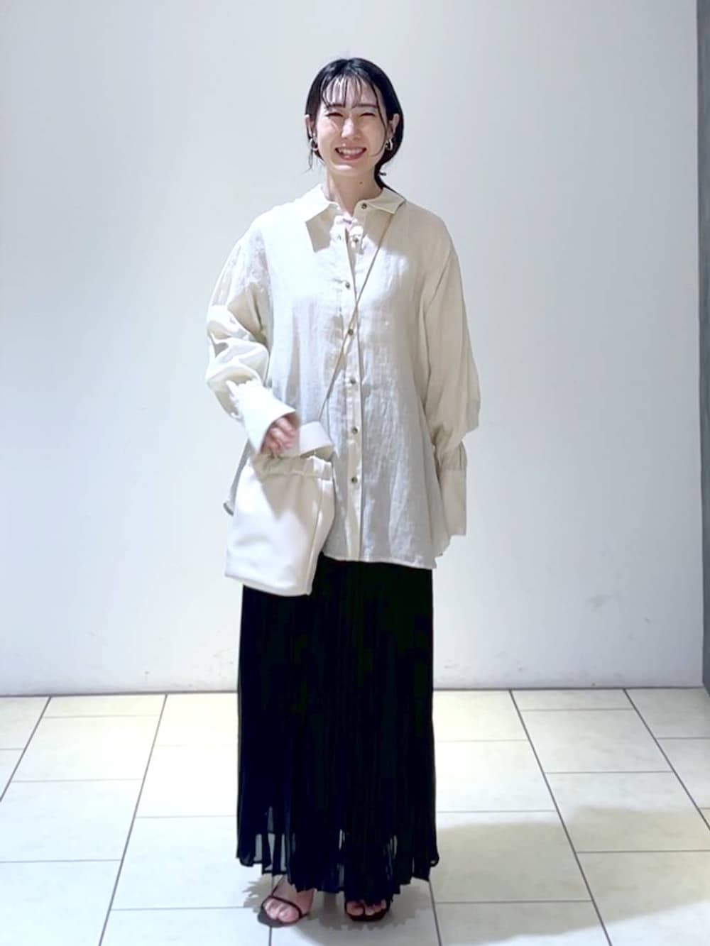 ベージュ系のシャツ/ブラウス、ブラック系のスカート、ホワイト系のショルダーバッグを着用したレディースの夏コーディネートの6枚目の写真