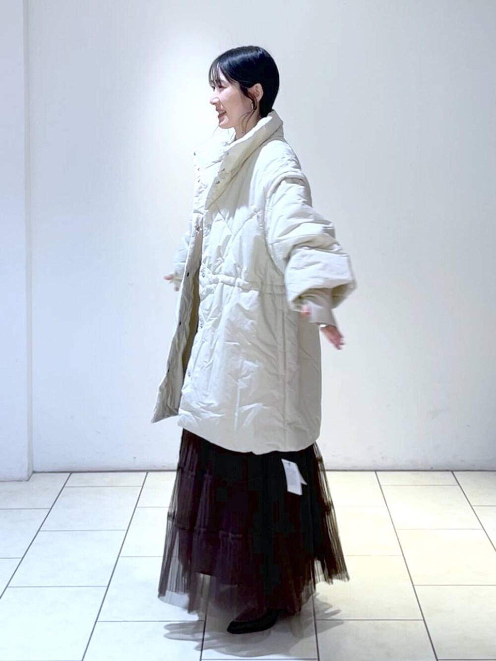 ピンク系のニット/セーター、ホワイト系のダウンジャケット/コート、ブラウン系のスカートを着用したレディースの冬コーディネートの4枚目の写真