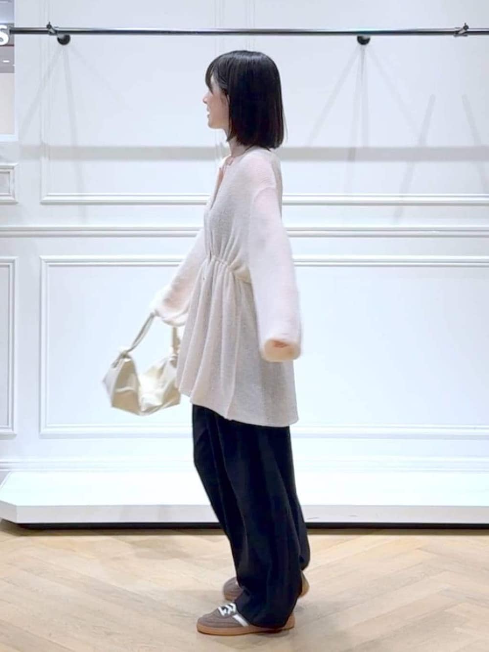 ブラック系のスラックス、ホワイト系のカーディガン/ボレロ、その他のネックレスを着用したレディースの春コーディネートの5枚目の写真