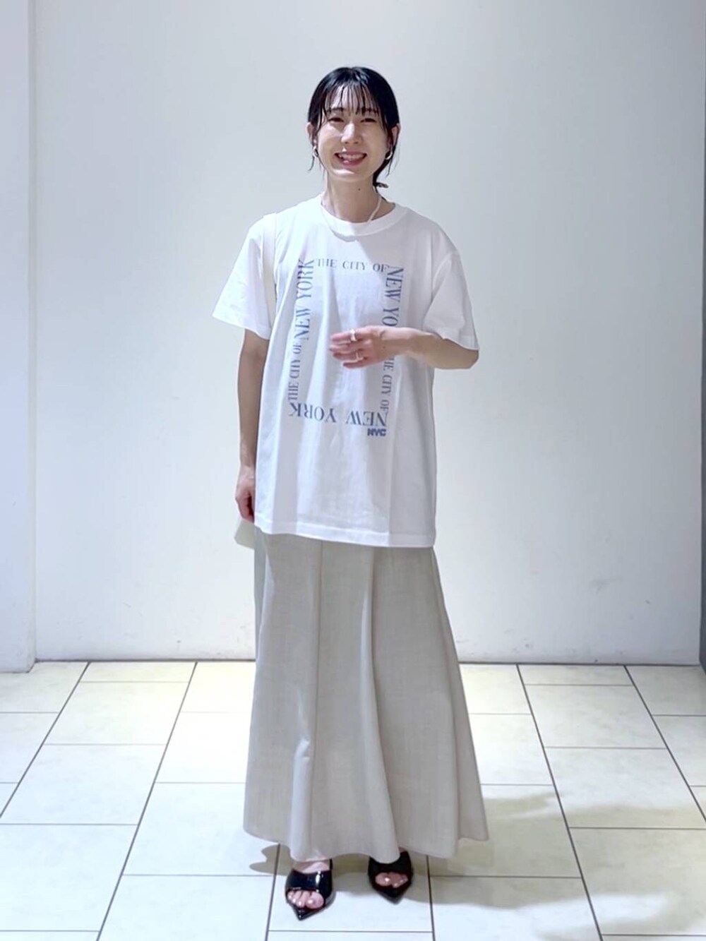 ブラック系のサンダル、ホワイト系のトートバッグ、ベージュ系のスカートを着用したレディースの夏コーディネートの6枚目の写真