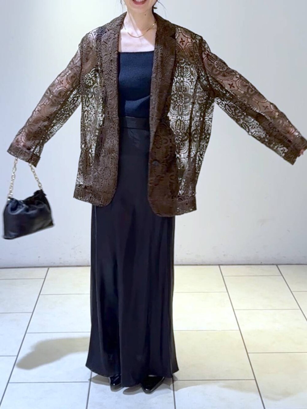 ブルー系のタンクトップ、ブラック系のスカート、ブラック系のパンプスを着用したレディースの春コーディネートの2枚目の写真