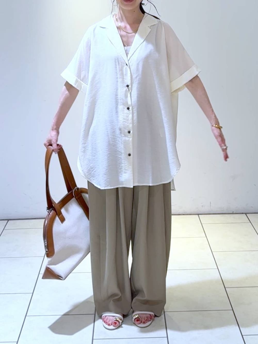 ベージュ系のスラックス、ホワイト系のシャツ/ブラウス、ブラウン系のトートバッグを着用したレディースの春コーディネートの2枚目の写真