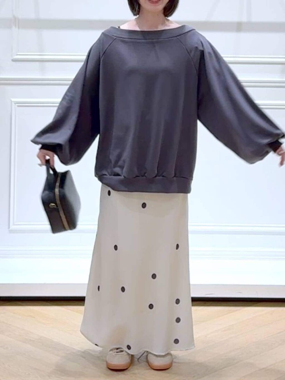 ベージュ系のスニーカー、グレー系のスウェット、ホワイト系のスカートを着用したレディースの春コーディネートの2枚目の写真