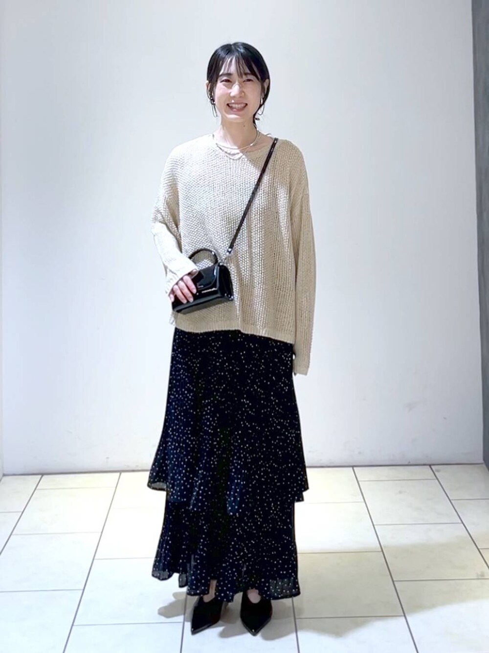 ベージュ系のニット/セーター、ブラック系のパンプス、グレー系のスカートを着用したレディースの秋コーディネートの6枚目の写真