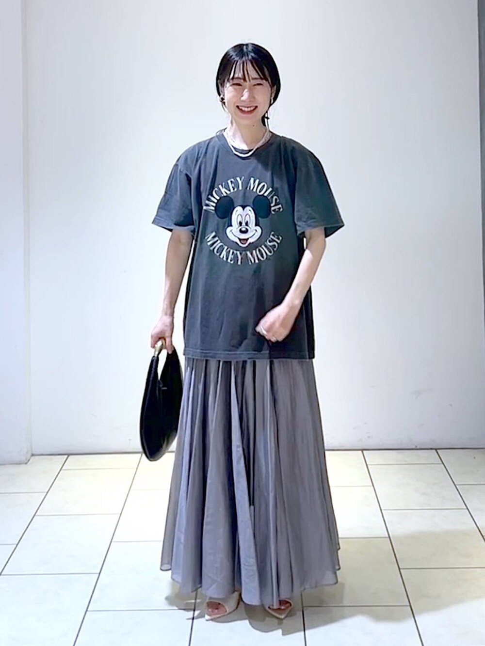 ホワイト系のサンダル、ブラック系のハンドバッグ、グレー系のスカートを着用したレディースの夏コーディネートの5枚目の写真