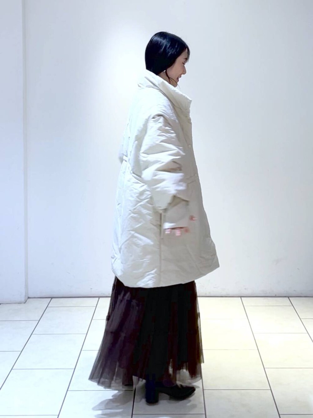 ピンク系のニット/セーター、ホワイト系のダウンジャケット/コート、ブラウン系のスカートを着用したレディースの冬コーディネートの2枚目の写真