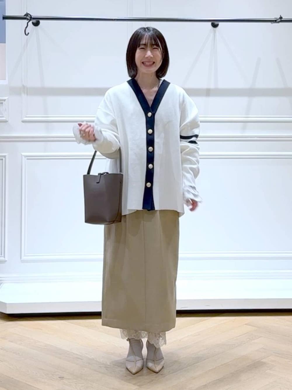 ブラック系のカーディガン/ボレロ、ベージュ系のスカート、ブラウン系のショルダーバッグを着用したレディースの春コーディネートの6枚目の写真