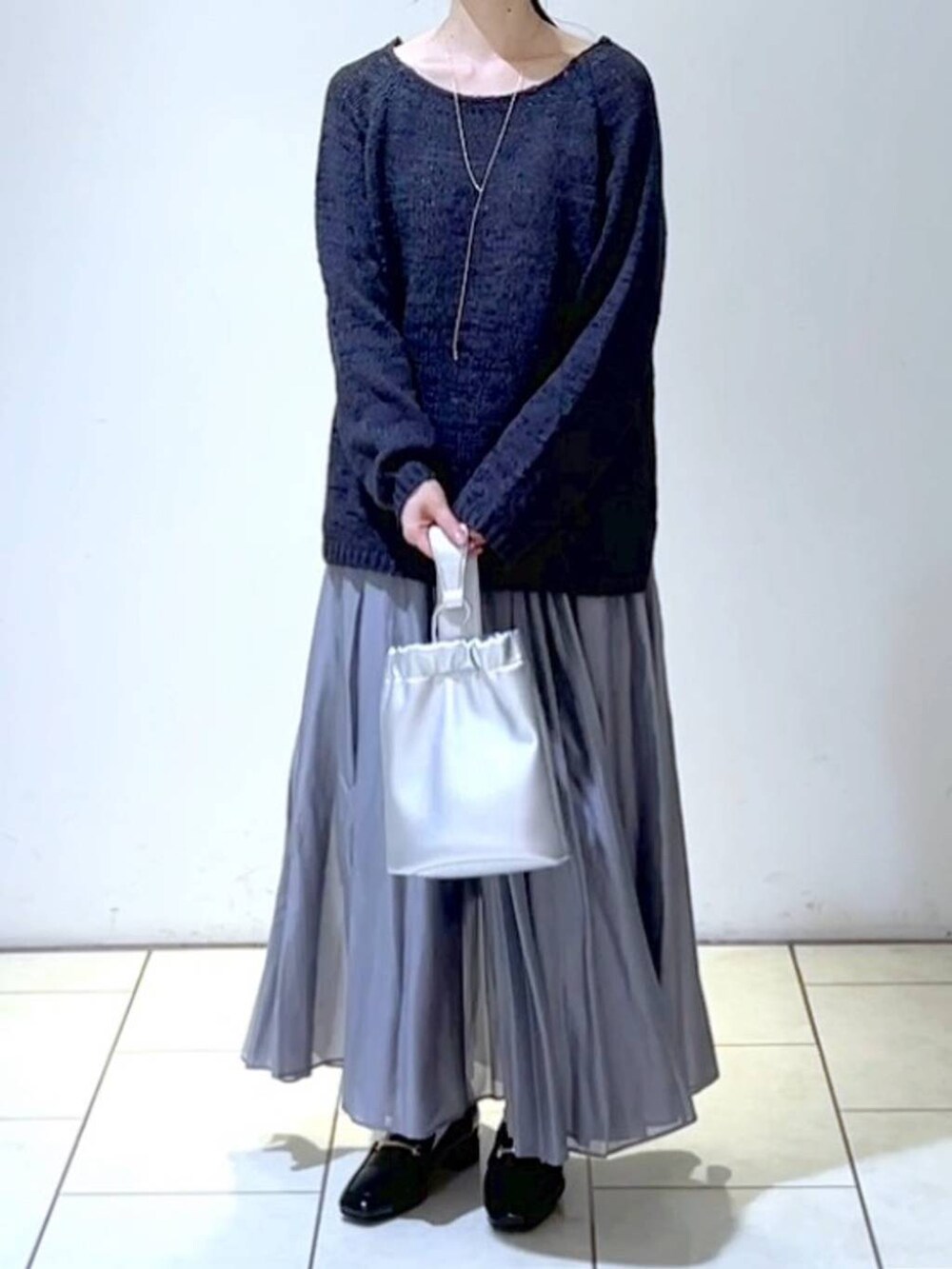 ブラック系のローファー、グレー系のスカート、シルバー系のショルダーバッグを着用したレディースの春コーディネートの2枚目の写真