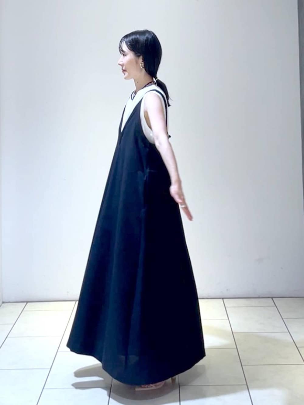 ホワイト系のサンダル、ブラック系のジャンパースカート、ホワイト系のショルダーバッグを着用したレディースの夏コーディネートの5枚目の写真