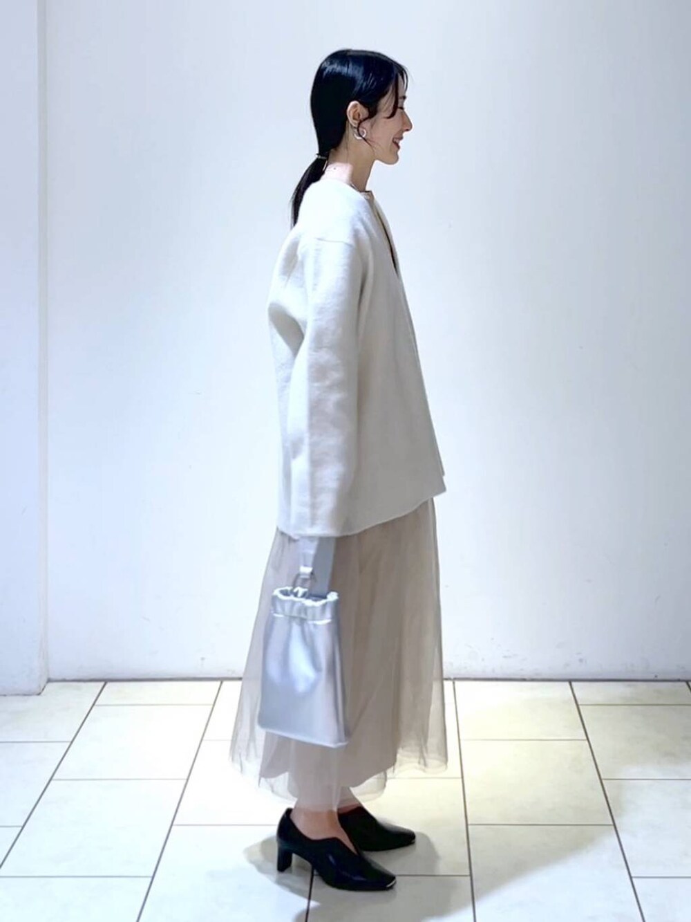 ベージュ系のワンピース、ホワイト系のニット/セーター、ブラック系のパンプスを着用したレディースの春コーディネートの3枚目の写真