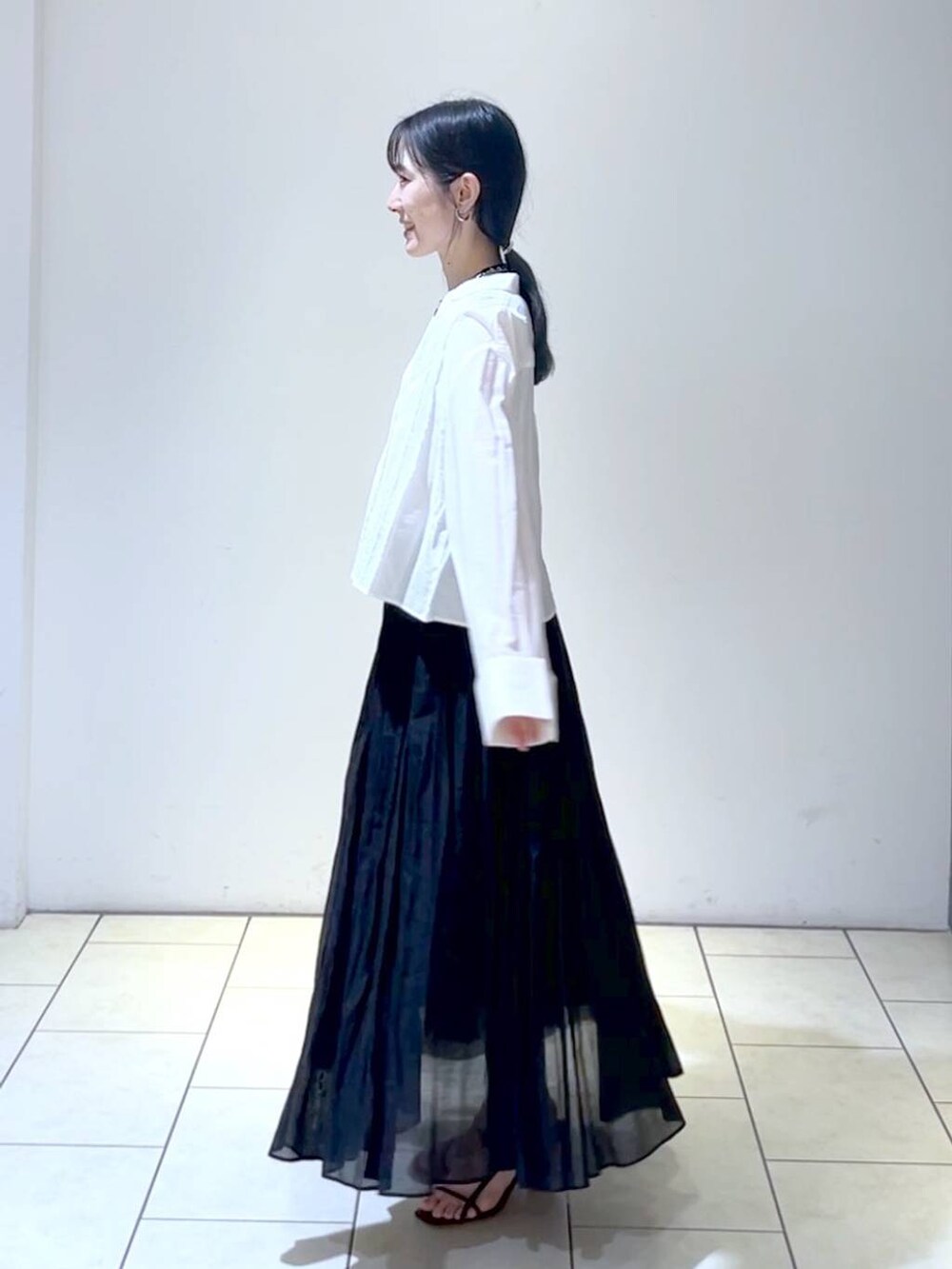 ブラック系のショルダーバッグ、ブラック系のスカート、ホワイト系のシャツ/ブラウスを着用したレディースの春コーディネートの5枚目の写真