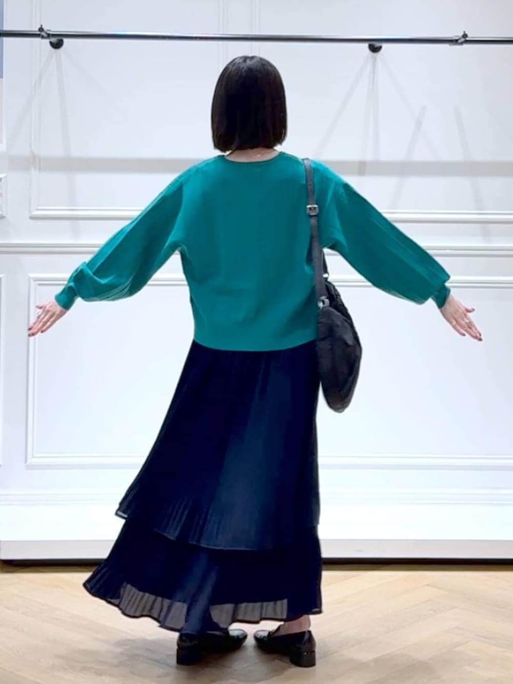 ブルー系のスカート、グリーン系のカーディガン/ボレロ、ブラック系のローファーを着用したレディースの春コーディネートの4枚目の写真