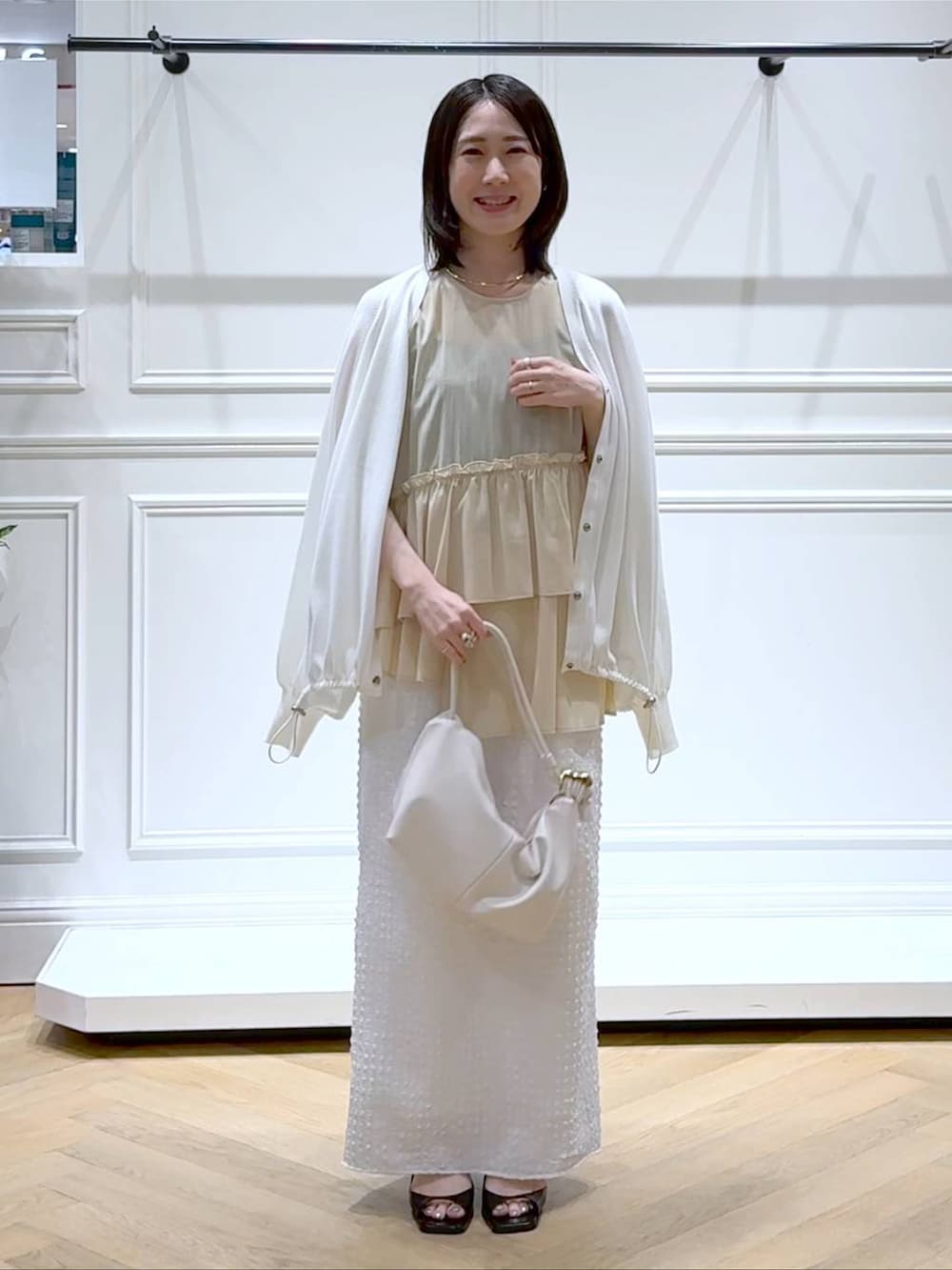 ホワイト系のカーディガン/ボレロ、ホワイト系のショルダーバッグ、ブラック系のパンプスを着用したレディースの夏コーディネートの6枚目の写真