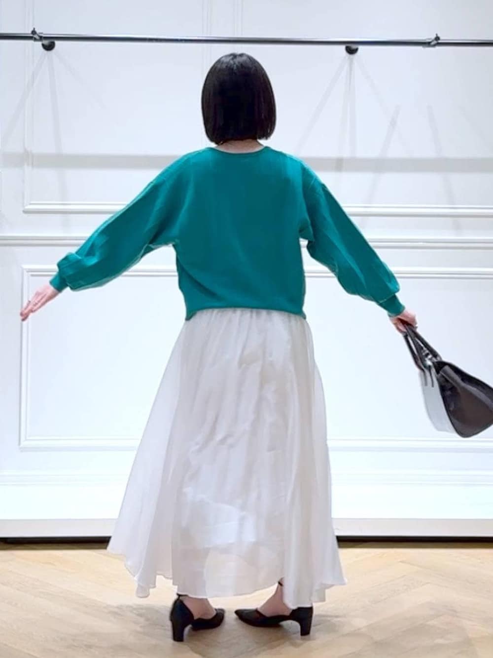 グリーン系のカーディガン/ボレロ、ホワイト系のスカート、ブラック系のパンプスを着用したレディースの春コーディネートの4枚目の写真