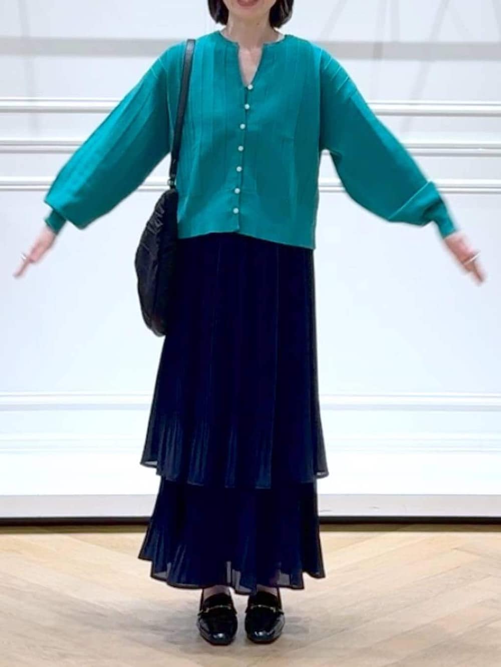 ブルー系のスカート、グリーン系のカーディガン/ボレロ、ブラック系のローファーを着用したレディースの春コーディネートの2枚目の写真