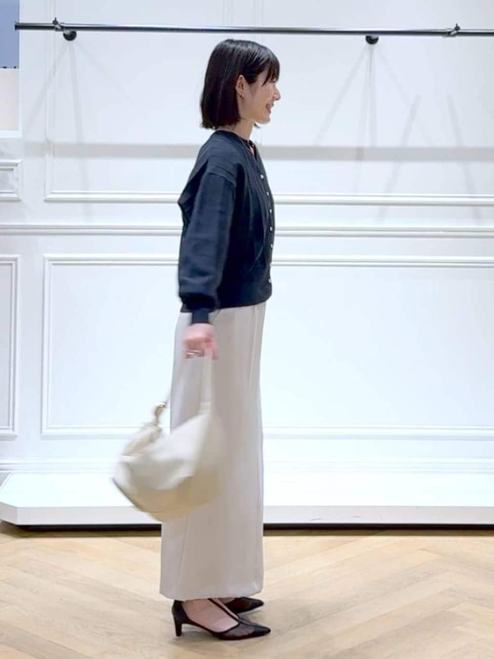 ブルー系のカーディガン/ボレロ、ブラック系のパンプス、ホワイト系のスカートを着用したレディースの春コーディネートの3枚目の写真