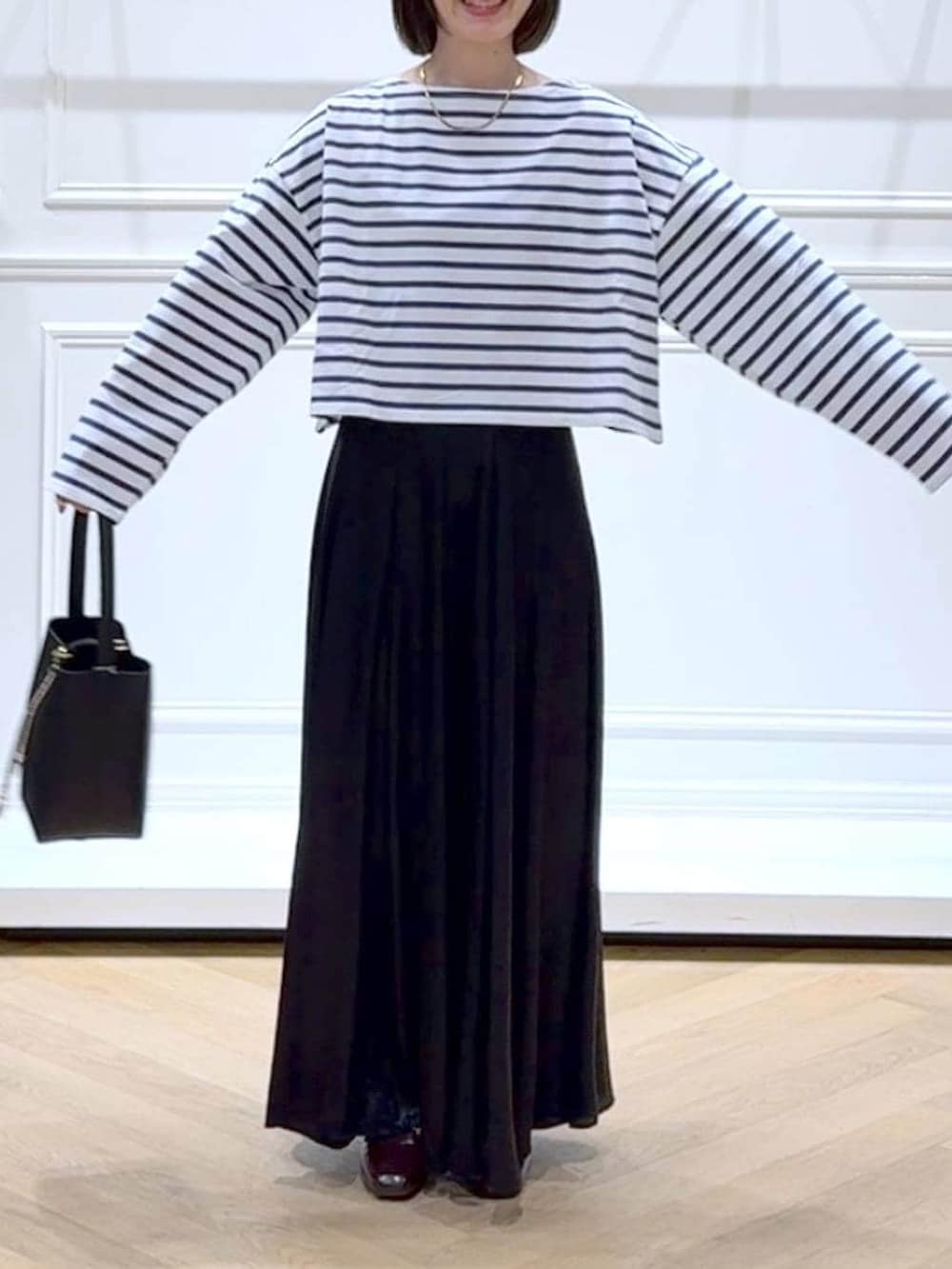 ブラック系のスカート、ブラウン系のローファー、ブラック系のショルダーバッグを着用したレディースの春コーディネートの2枚目の写真