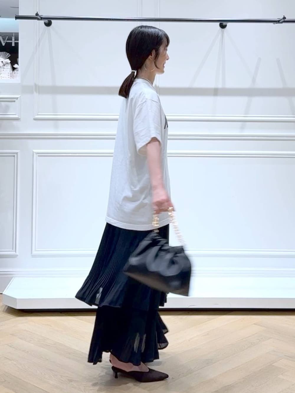 ブラック系のスカート、ホワイト系のTシャツ/カットソー、ブラウン系のパンプスを着用したレディースの秋コーディネートの3枚目の写真