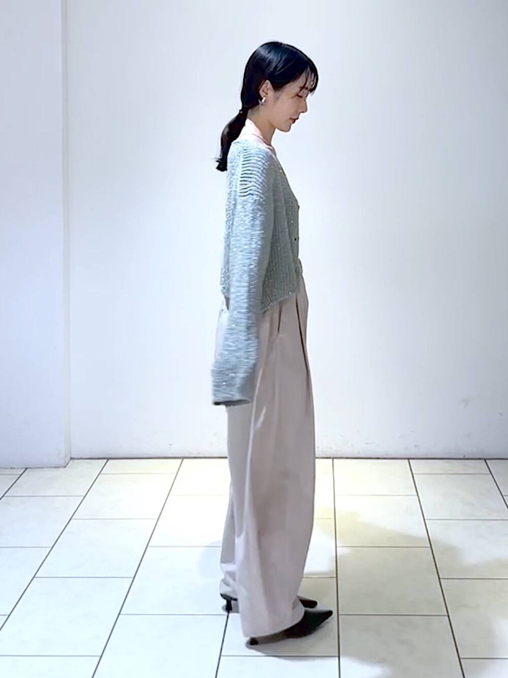 グレー系のカーディガン/ボレロ、ブラック系のパンプス、ホワイト系のショルダーバッグを着用したレディースの秋コーディネートの2枚目の写真