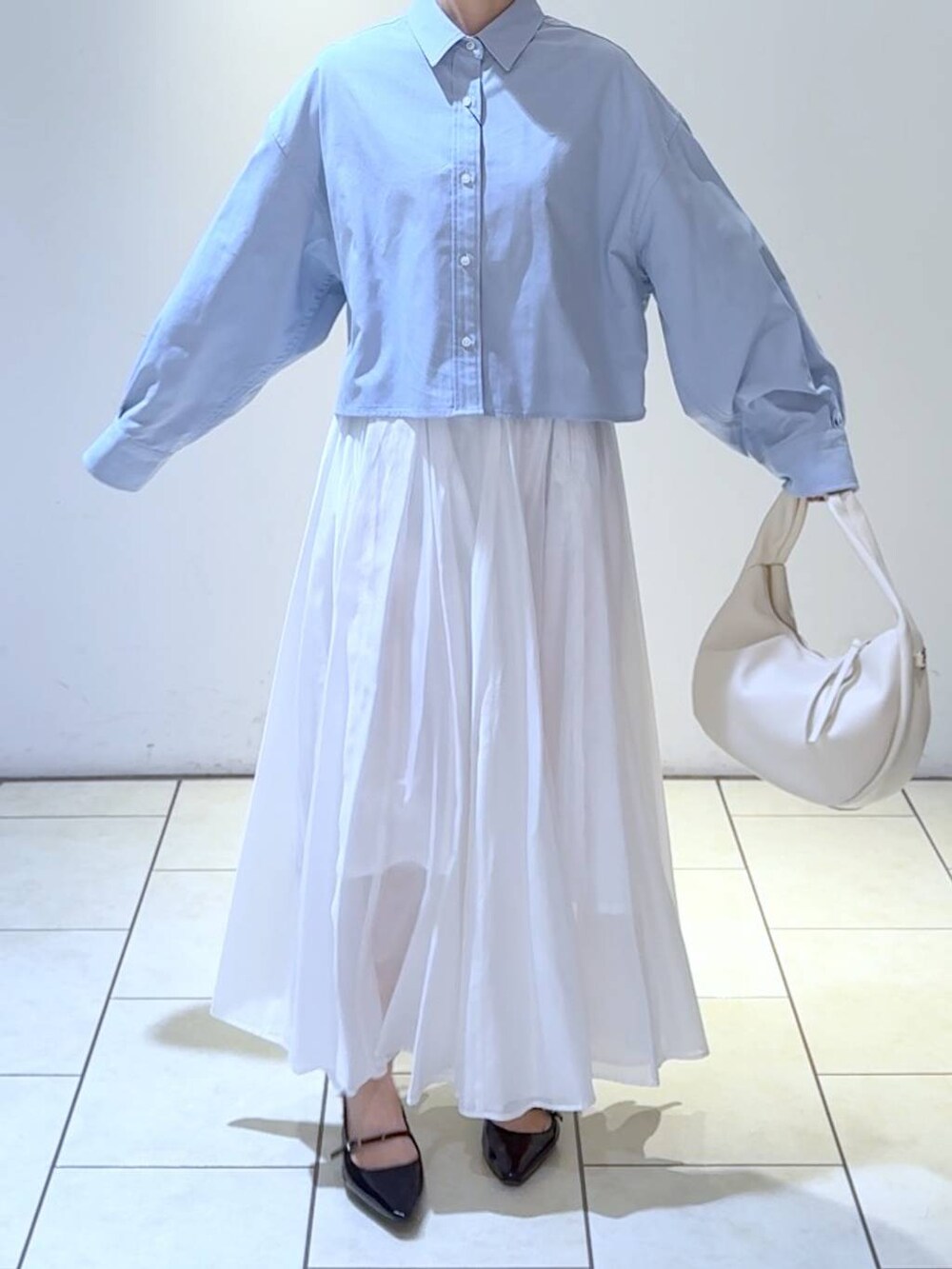 ホワイト系のハンドバッグ、ブルー系のシャツ/ブラウス、ブラック系のパンプスを着用したレディースの冬コーディネートの5枚目の写真