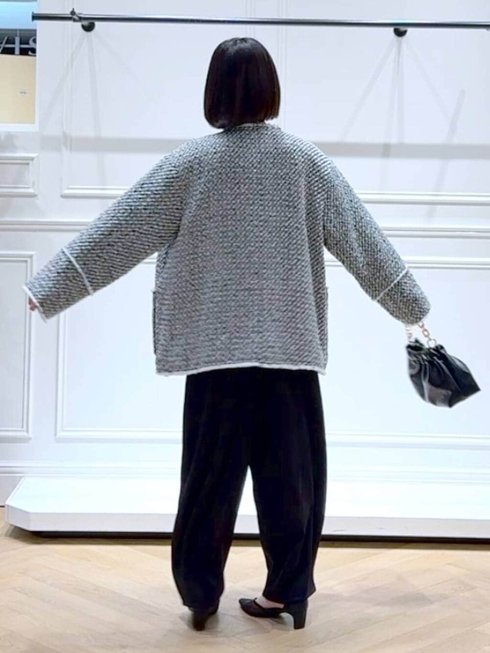 ブラック系のショルダーバッグ、ブラック系のスラックス、ブラック系のノーカラージャケットを着用したレディースの春コーディネートの4枚目の写真