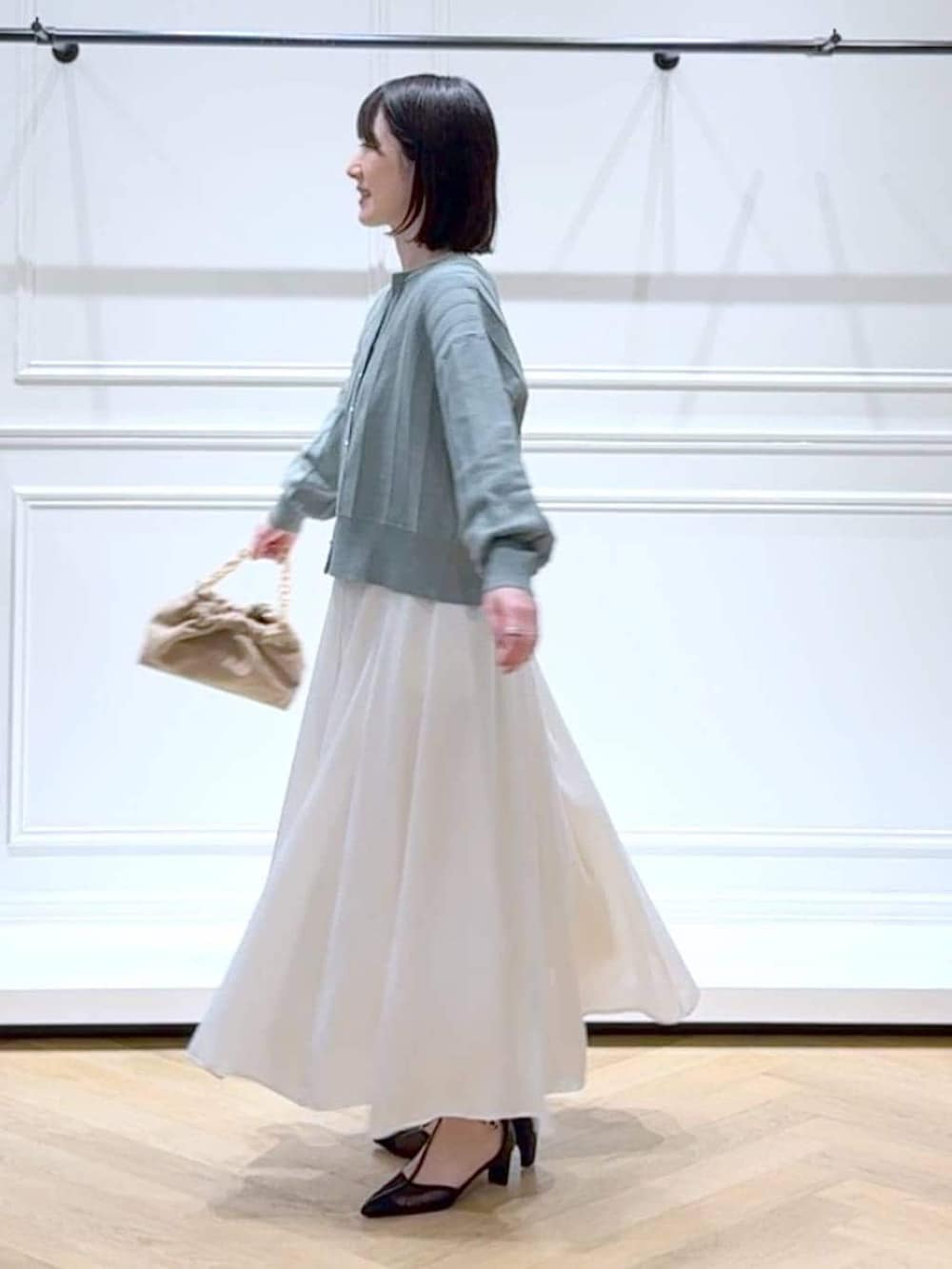 グリーン系のカーディガン/ボレロ、ベージュ系のショルダーバッグ、ホワイト系のスカートを着用したレディースの春コーディネートの5枚目の写真