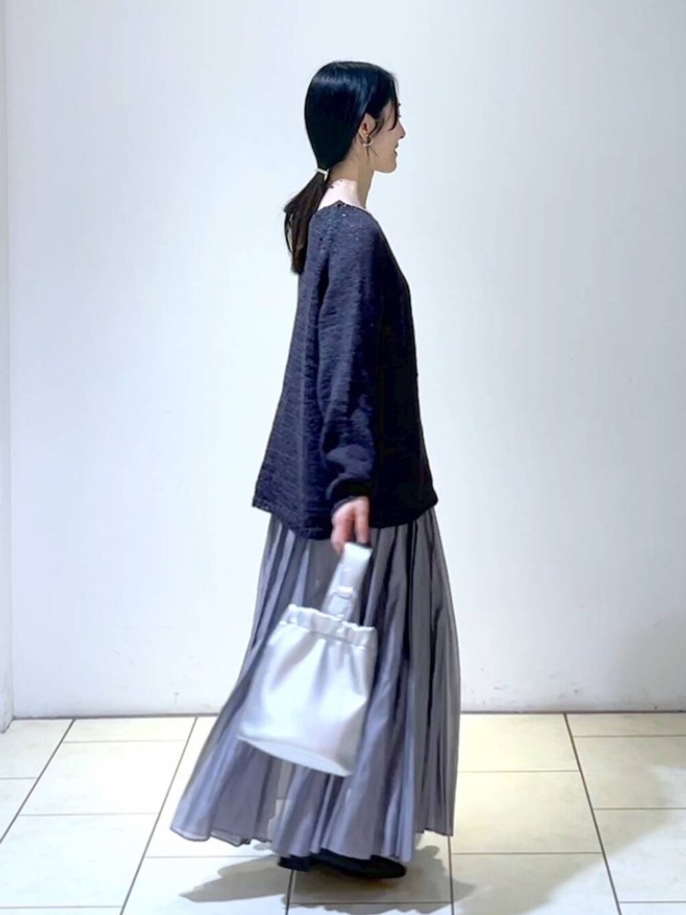 ブラック系のローファー、グレー系のスカート、シルバー系のショルダーバッグを着用したレディースの春コーディネートの3枚目の写真