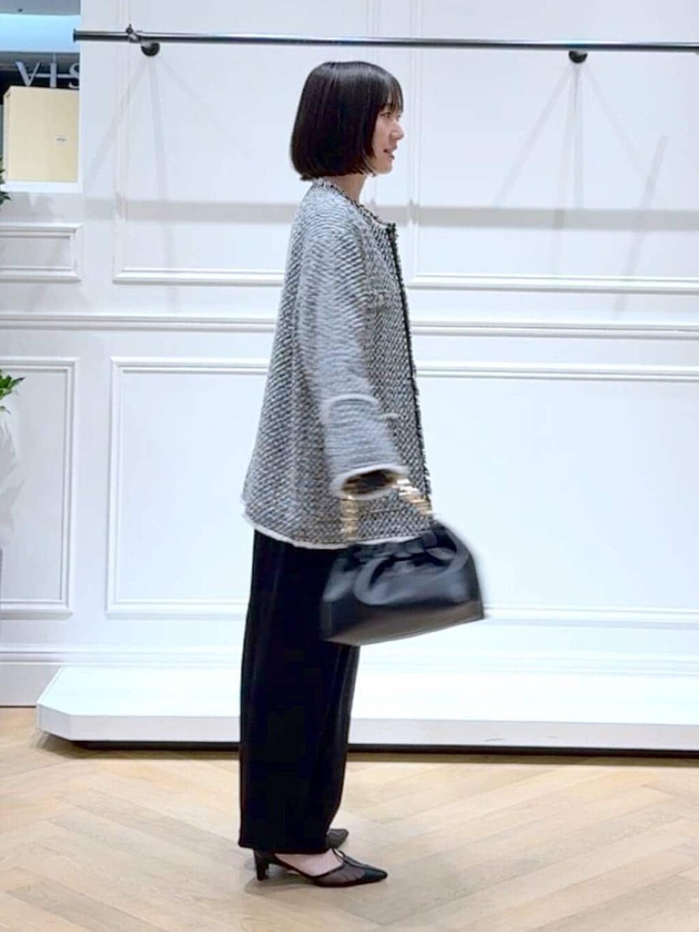 ブラック系のショルダーバッグ、ブラック系のスラックス、ブラック系のノーカラージャケットを着用したレディースの春コーディネートの3枚目の写真