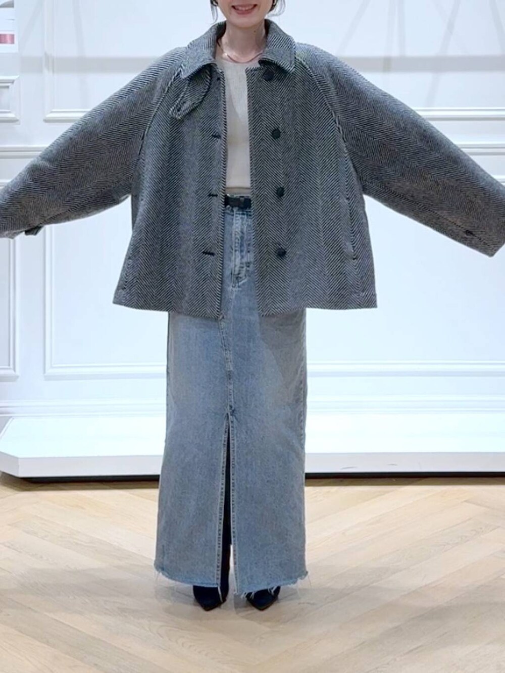 ホワイト系のニット/セーター、ブルー系のデニムスカート、ブラック系のブーツを着用したレディースの秋コーディネートの2枚目の写真