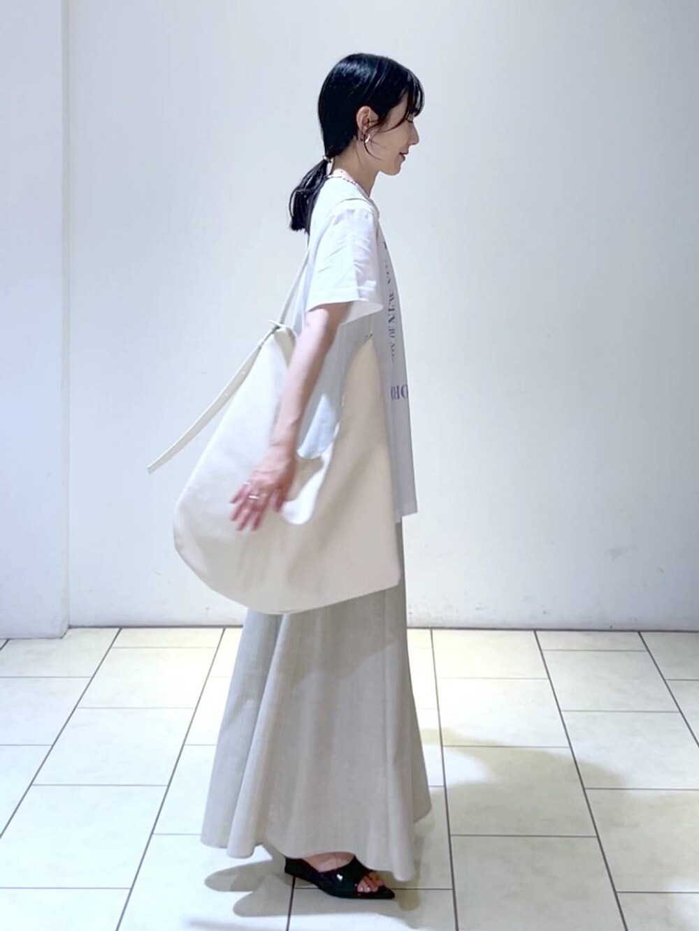ブラック系のサンダル、ホワイト系のトートバッグ、ベージュ系のスカートを着用したレディースの夏コーディネートの3枚目の写真