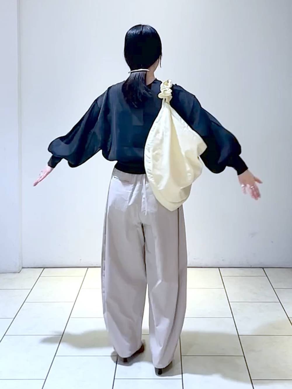 ブラック系のニット/セーター、ブラック系のパンプス、ホワイト系のショルダーバッグを着用したレディースの秋コーディネートの4枚目の写真