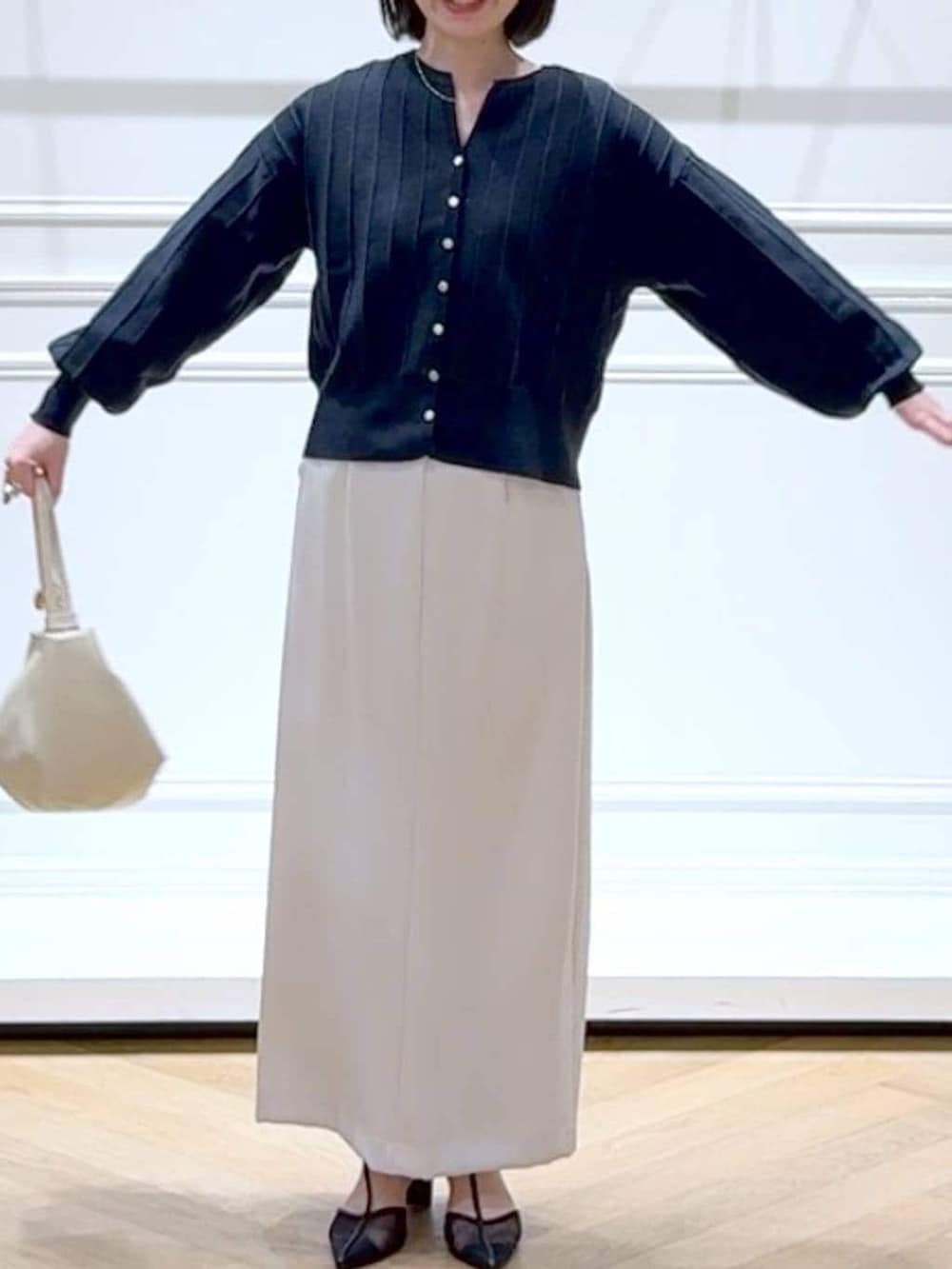 ブルー系のカーディガン/ボレロ、ブラック系のパンプス、ホワイト系のスカートを着用したレディースの春コーディネートの2枚目の写真