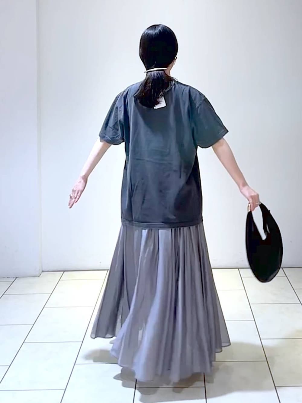 ホワイト系のサンダル、ブラック系のハンドバッグ、グレー系のスカートを着用したレディースの夏コーディネートの4枚目の写真