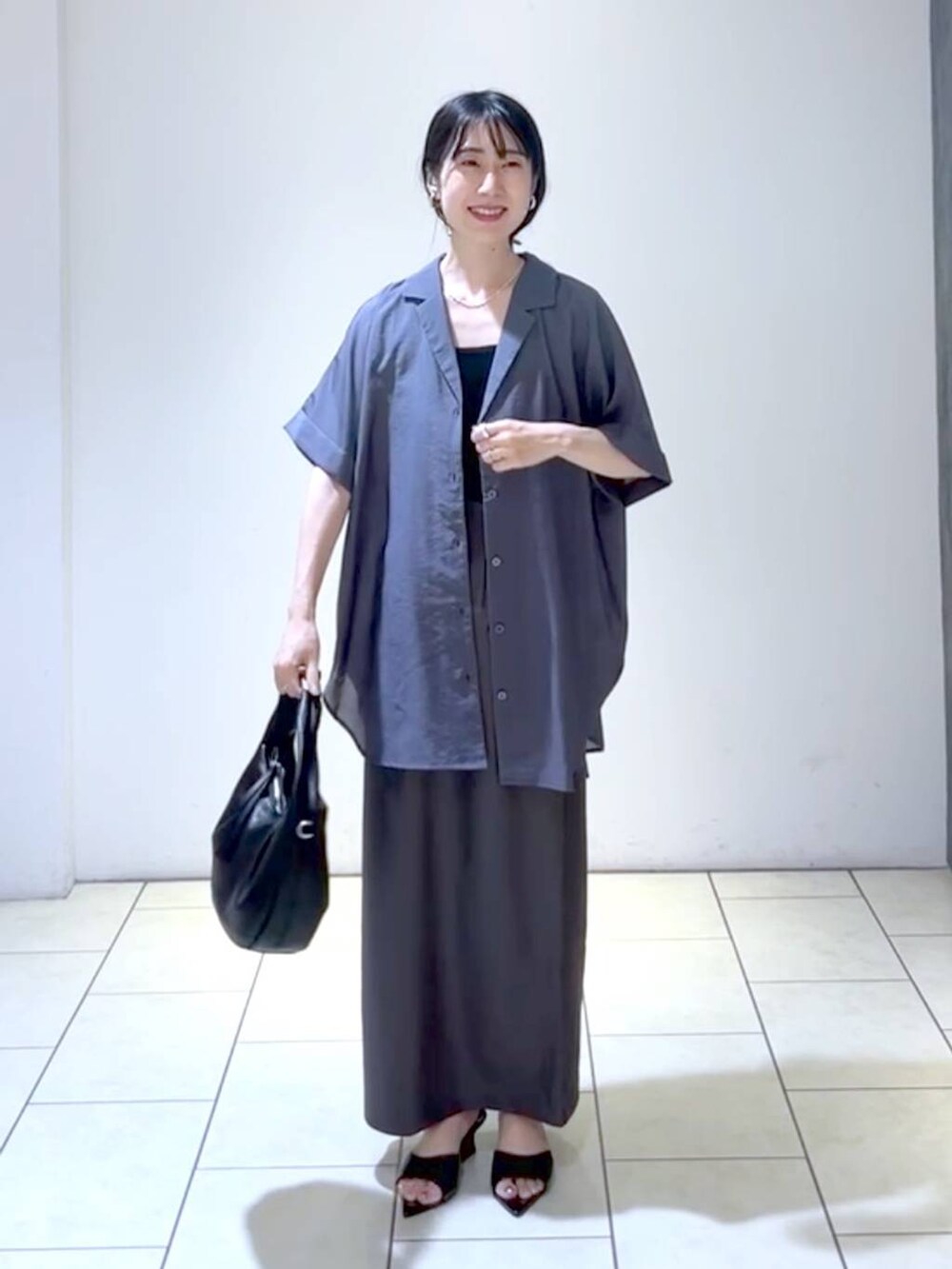 ブラック系のサンダル、ブラック系のハンドバッグ、ブラック系のタンクトップを着用したレディースの夏コーディネートの6枚目の写真