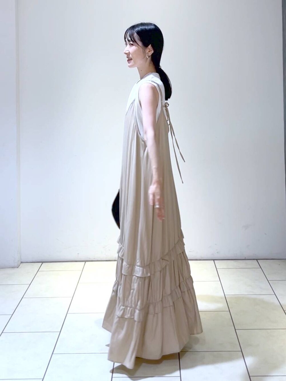 ホワイト系のサンダル、ブラック系のハンドバッグ、ベージュ系のワンピースを着用したレディースの夏コーディネートの5枚目の写真