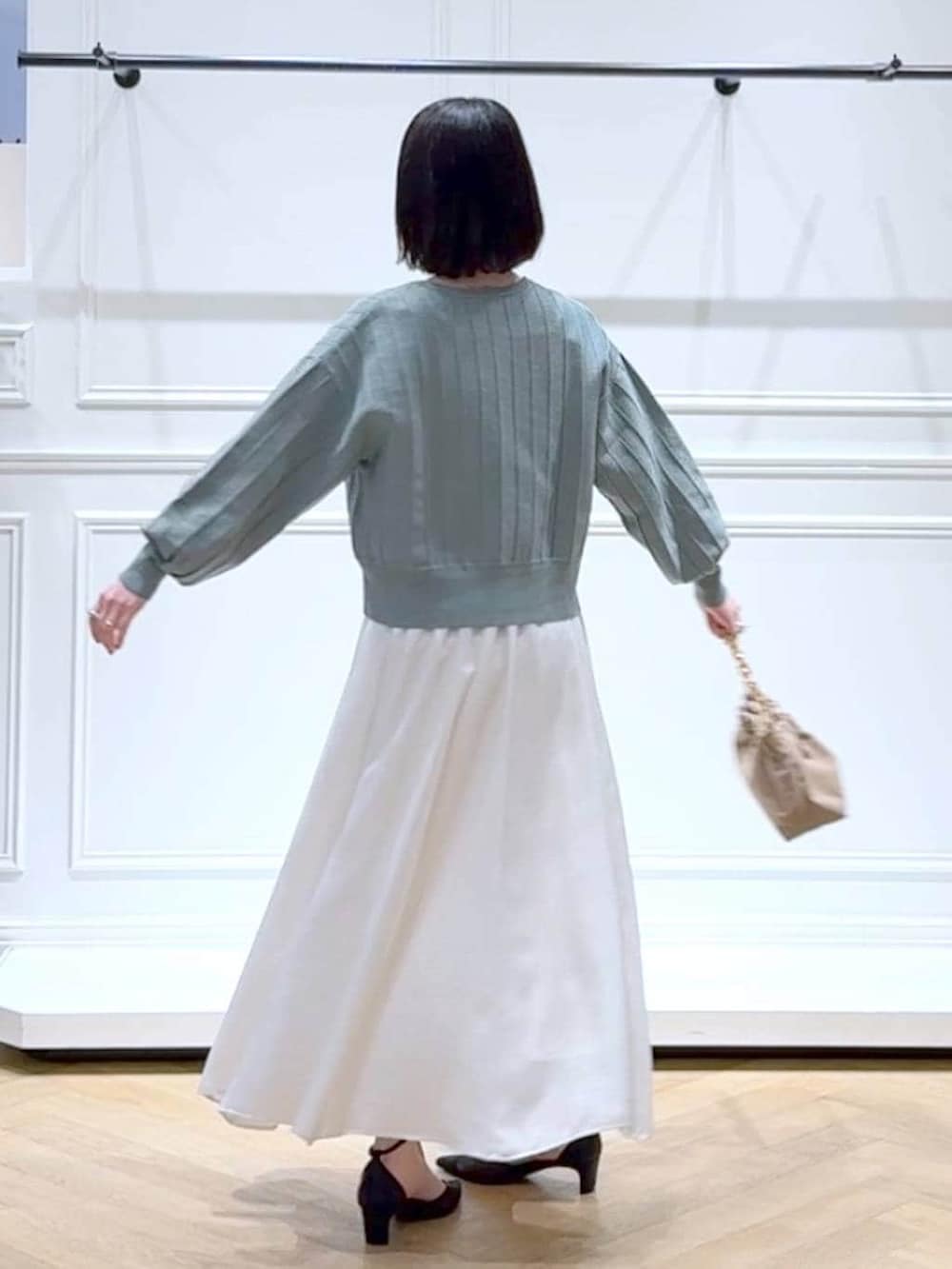 グリーン系のカーディガン/ボレロ、ベージュ系のショルダーバッグ、ホワイト系のスカートを着用したレディースの春コーディネートの4枚目の写真