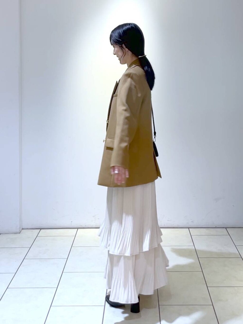 イエロー系のテーラードジャケット、ホワイト系のニット/セーター、ホワイト系のスカートを着用したレディースの秋コーディネートの5枚目の写真