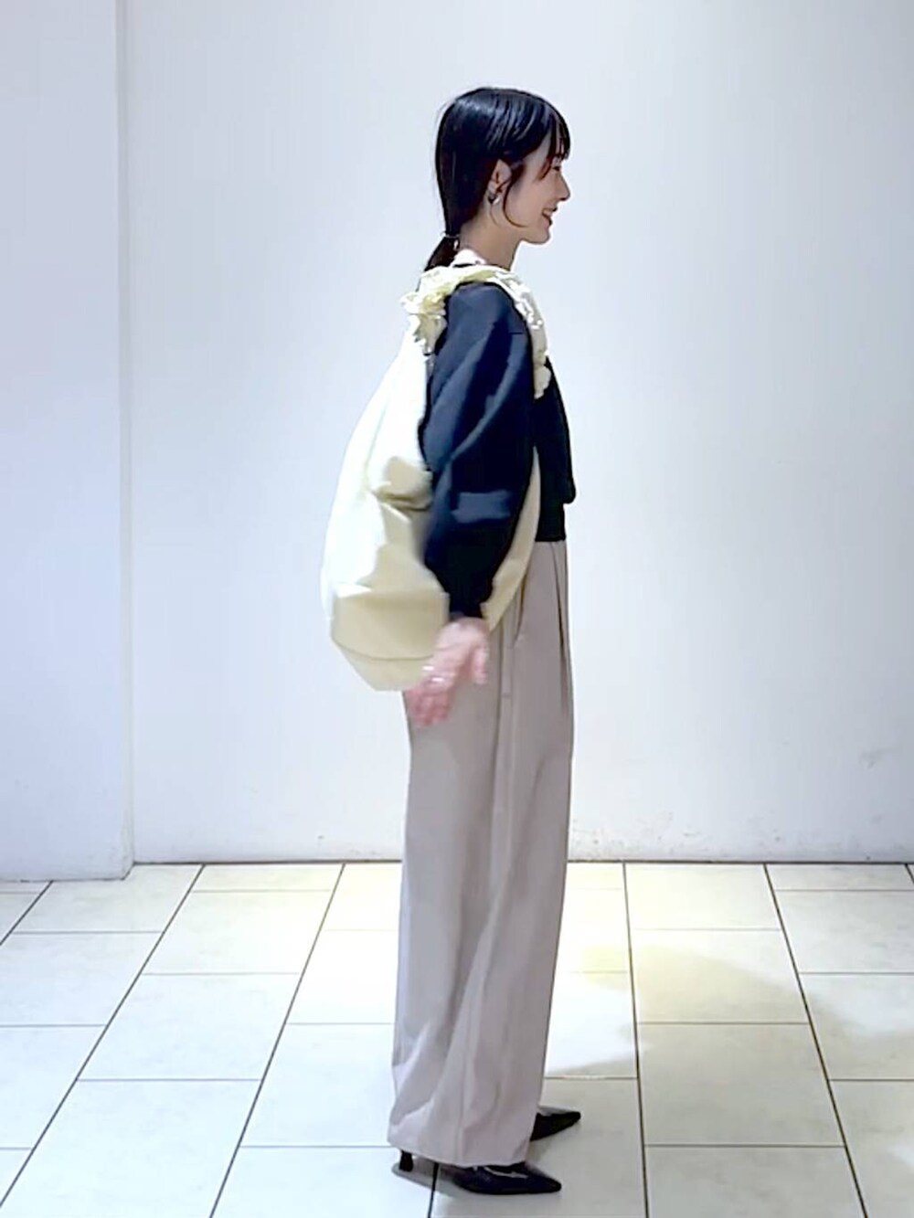 ブラック系のニット/セーター、ブラック系のパンプス、ホワイト系のショルダーバッグを着用したレディースの秋コーディネートの3枚目の写真